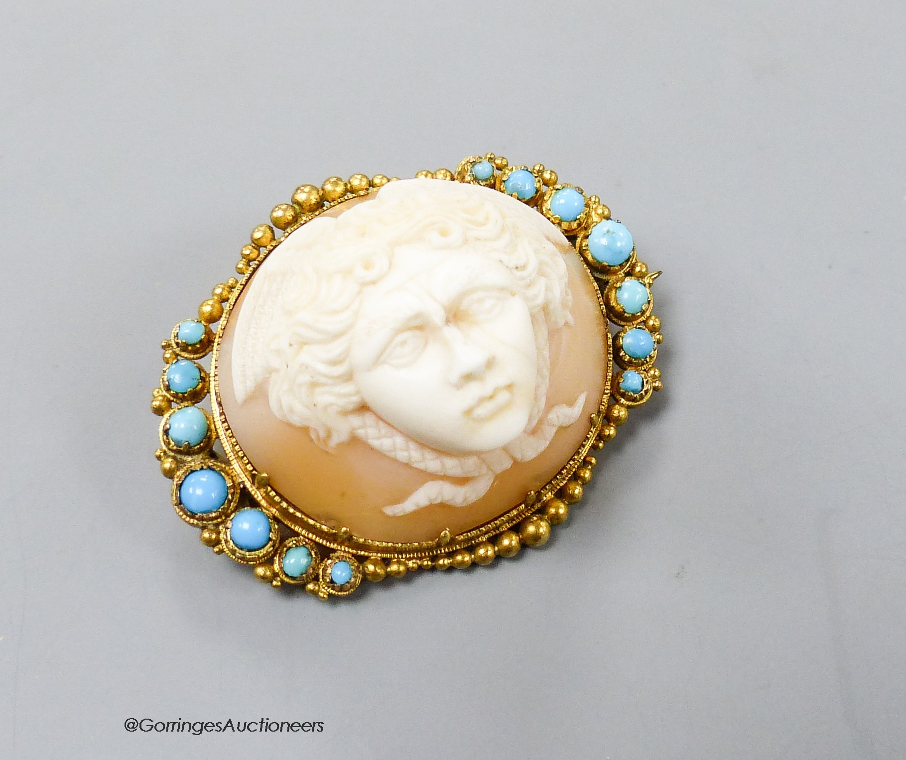 A Victorian yellow metal mounted cameo shell and turquoise set oval brooch, carved with the head of a cherub, 34mm, gross 9.2 grams.